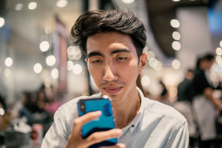 Man using mobile phone in illuminated restaurant