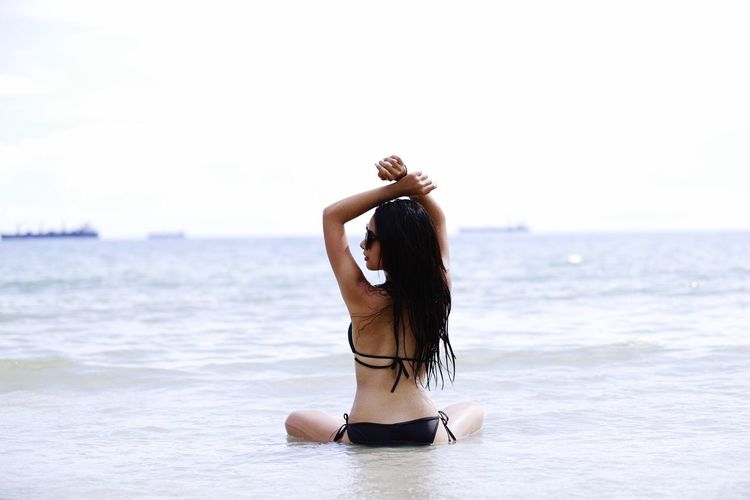 Rear view of sensuous woman wearing bikini in sea at beach