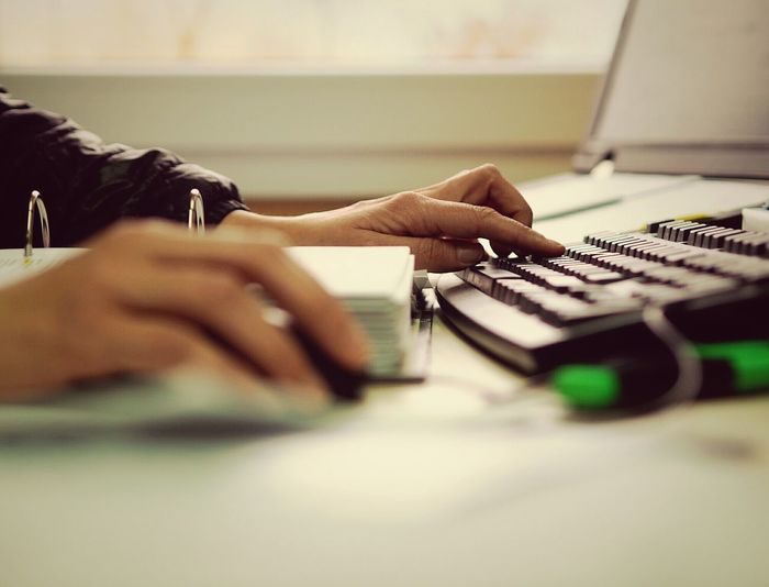 Cropped image of woman using keyboard at desk at office