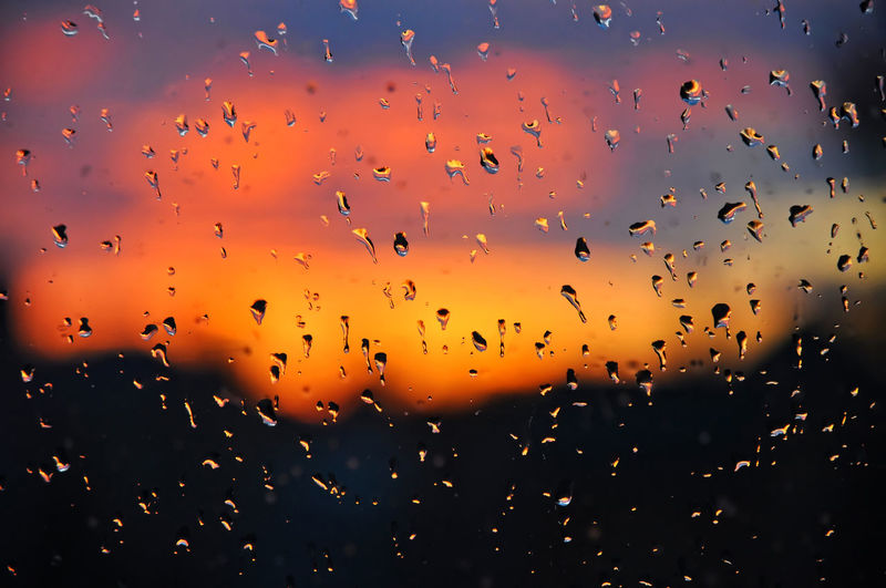 Full frame shot of wet glass window during sunset