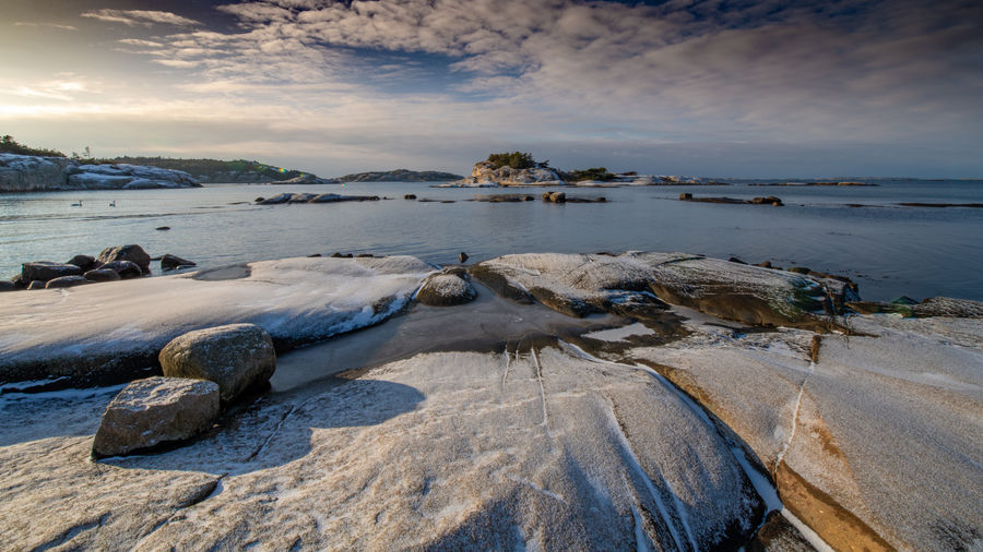 Rocks on beach against sky during sunset