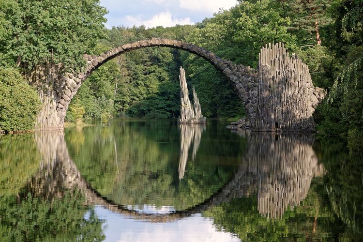 Arch bridge over lake against sky