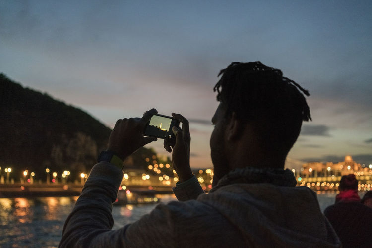 African male taking image from a boat at night in budapest