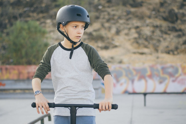 Portrait of trendy young skater wearing helmet looking away. teenager enjoying sunny day in the city