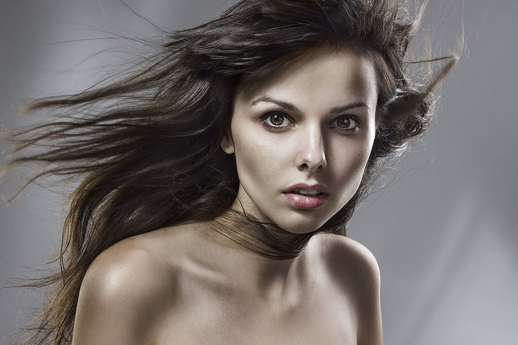 Portrait of shirtless woman with tousled hair against gray background