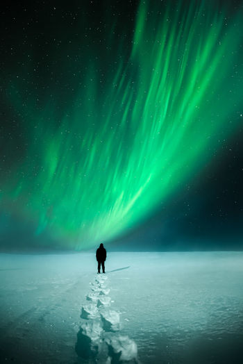 Rear view of person standing in snow against sky at night