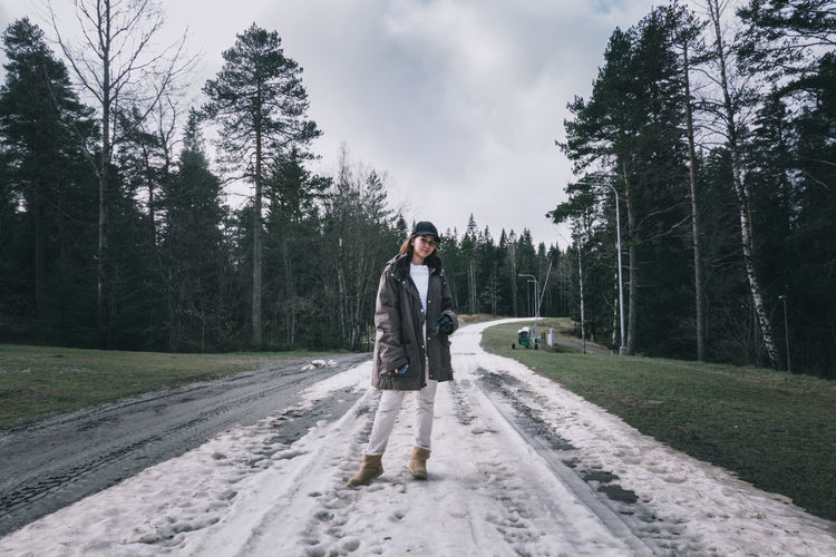 Man standing on road amidst trees in forest