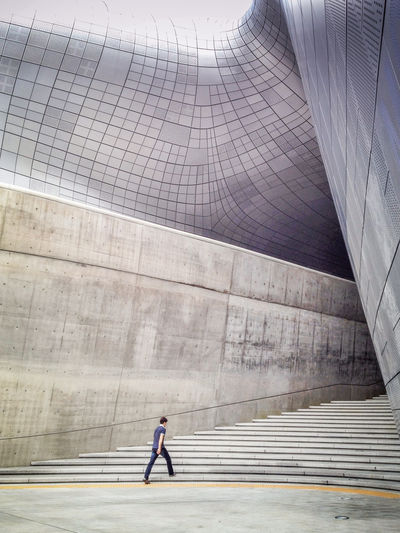 Man walking on steps at dongdaemun design plaza in city