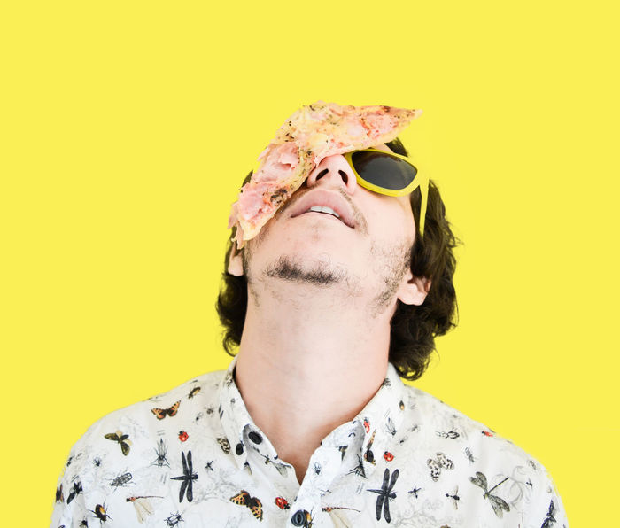 Close-up portrait of man with pizza on face