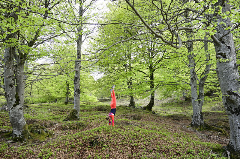 Woman doing handstand in middle of forest