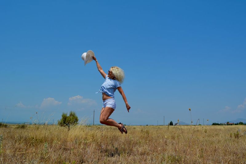 Full length of man jumping on field against sky