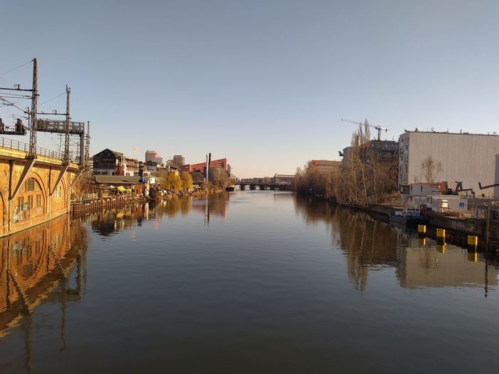 Reflection of buildings in river against clear sky
