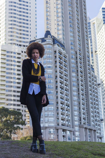 Portrait of young woman standing against modern buildings in city