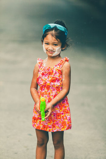 Portrait of cute girl holding squirt gun outdoors