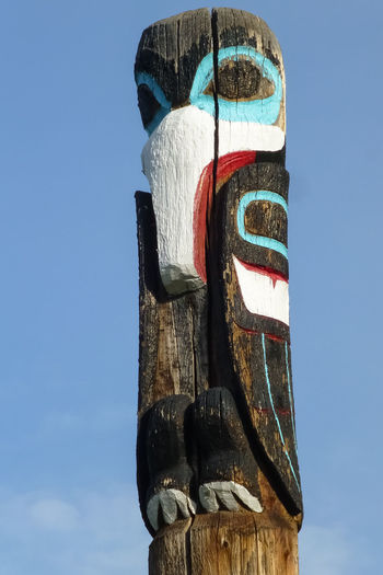 Low angle view of totem pole sculpture against blue sky