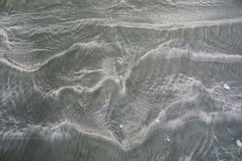 Texture of black sand beach at a sea