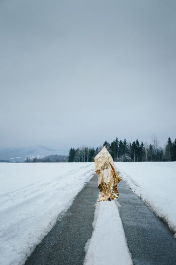 Full length of person covered with foil standing on snowy road