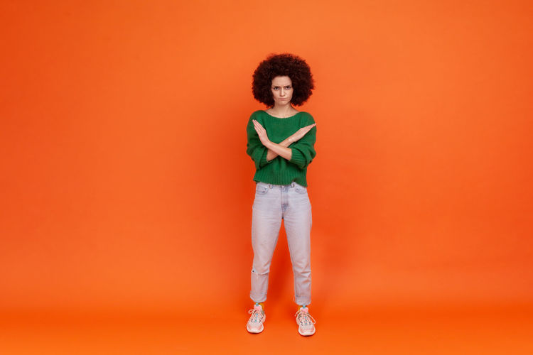 Full length portrait of woman gesturing against colored background