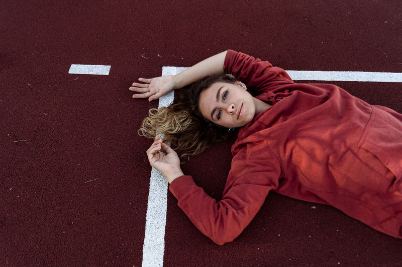 High angle view of young woman lying on sports track