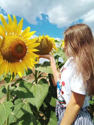 Low angle view of woman by sunflower against sky