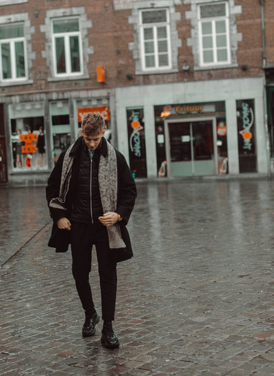 Full length of man standing on street in rain