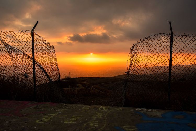 Scenic view of sunset seen through chainlink fence