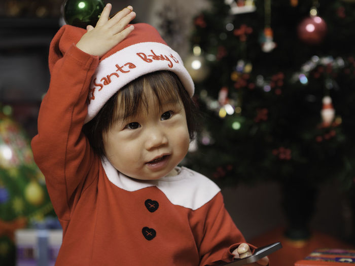Cute girl wearing costume standing by christmas tree at home