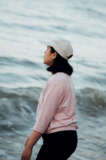 Side view of woman standing against sea