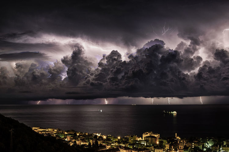 View of illuminated city against storm clouds at night