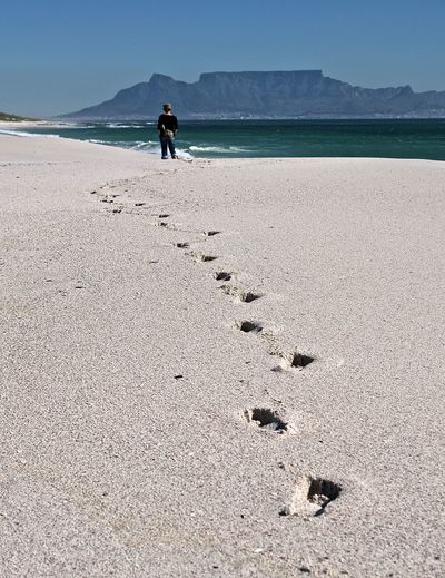 Footprint on sandy beach against sky during sunny day