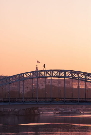 View of bridge against clear sky during sunrise, with a urban climber on top of it. 