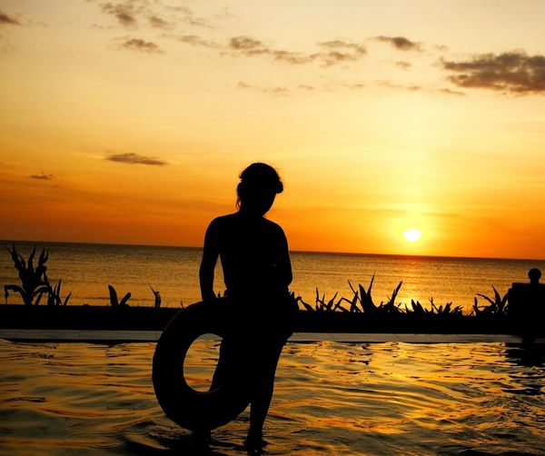 Silhouette man standing at beach during sunset