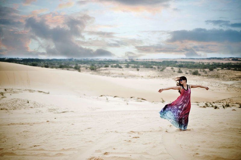 View of woman in tie dye dress standing on beach