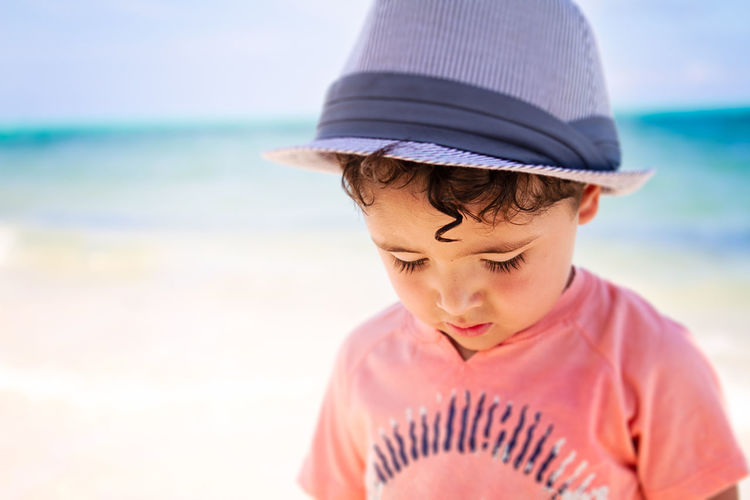Little boy with curly hair walking a the beach in the caribbean