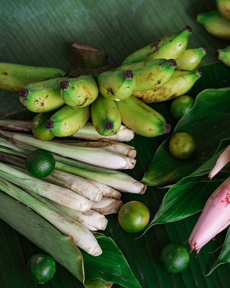 Asian food ingredient lemongrass, calamansi, tumeric leaves and bananas on a banana leaf background.