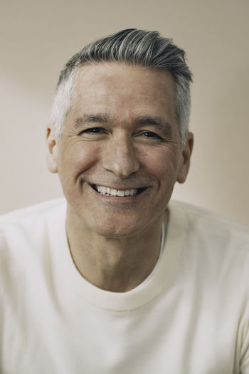 Portrait of cheerful mature man against beige background