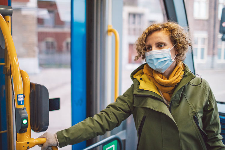 Woman wearing mask standing in bus