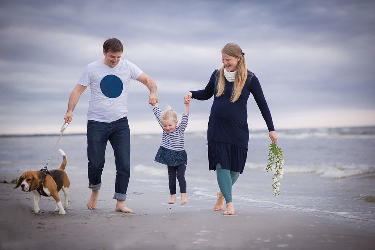 Full length of happy family walking at beach