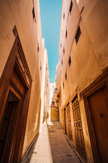 Low angle view of narrow alley amidst buildings in city
