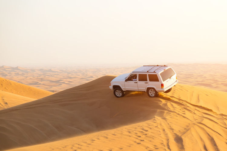Car on desert against clear sky