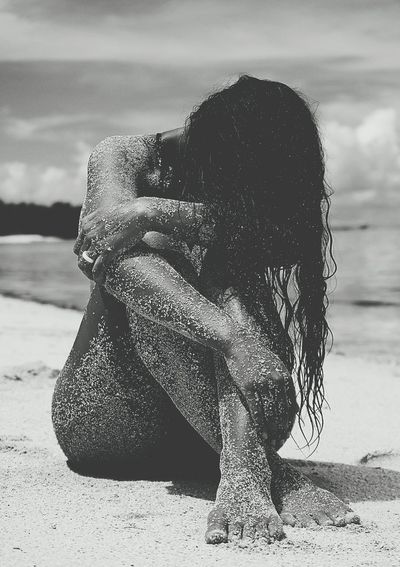 Naked messy woman sitting at beach