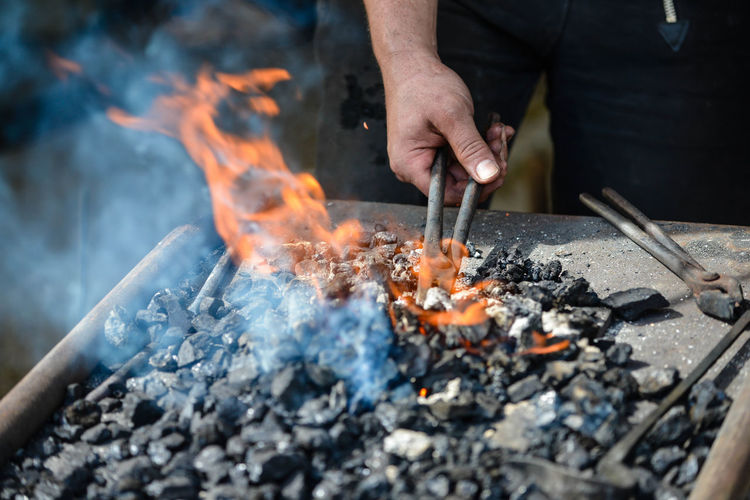 Low angle view of man preparing fire on barbecue grill