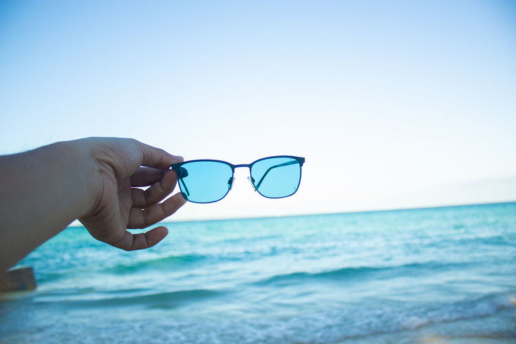 Man wearing sunglasses against sea against clear sky