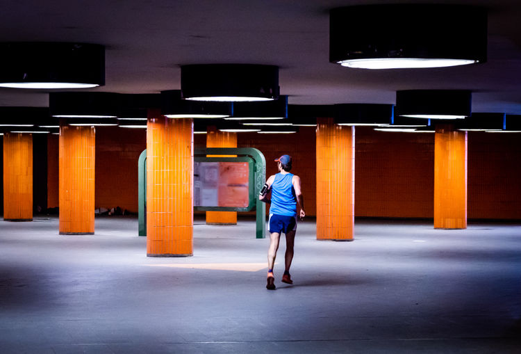 Full length rear view of man jogging in illuminated subway