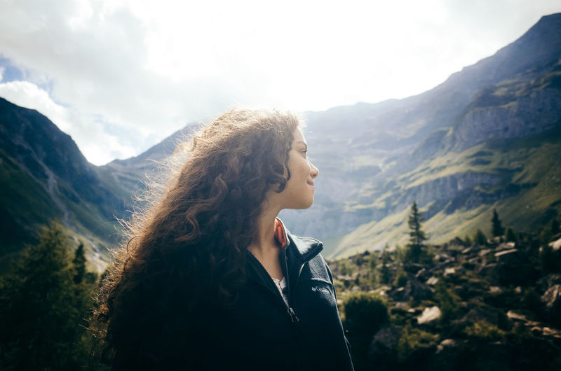 Close-up young woman standing on mountain against sky