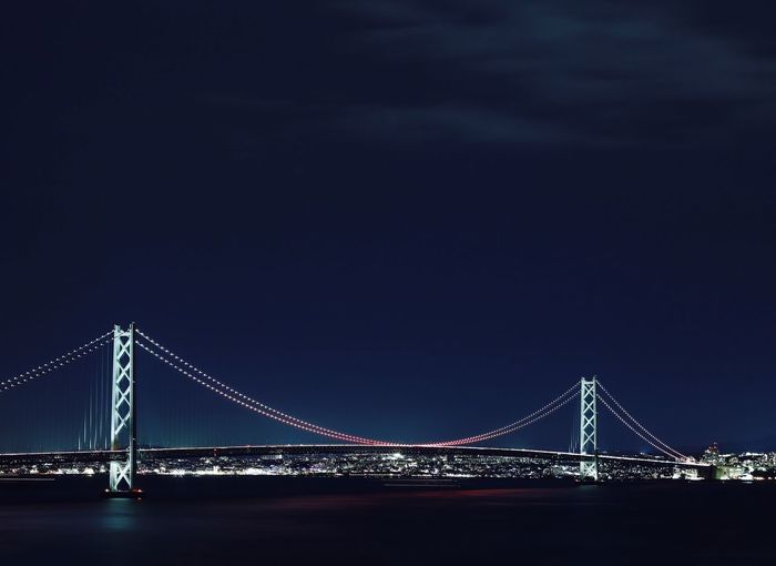 Illuminated akashi strait bridge over sea against clear sky at night