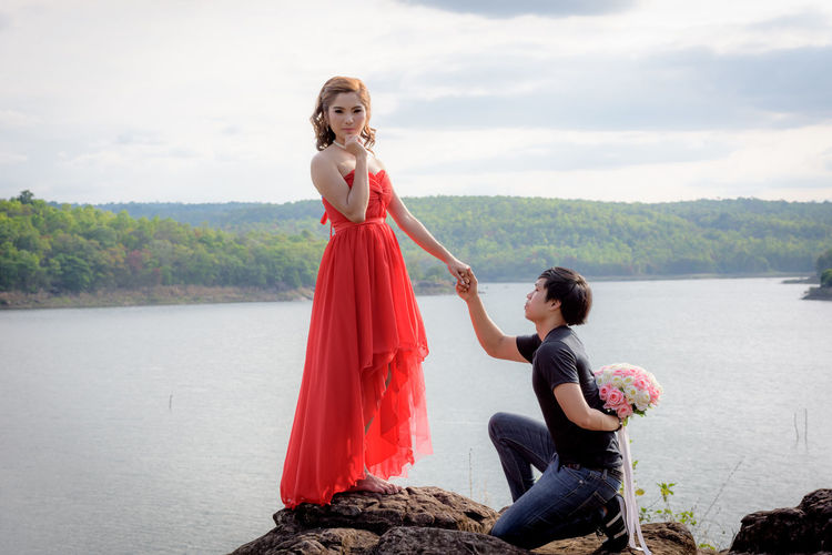 Boyfriend proposing girlfriend on rock by lake