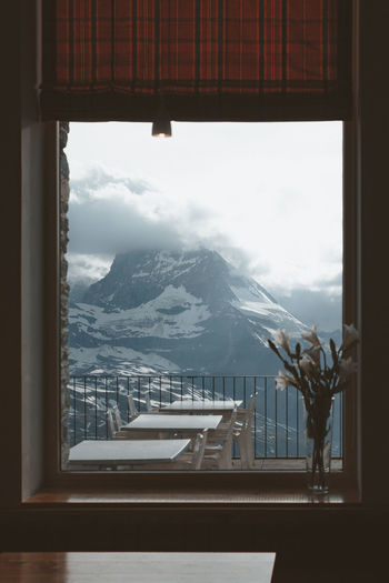 Scenic view of snowcapped mountains against sky seen through window