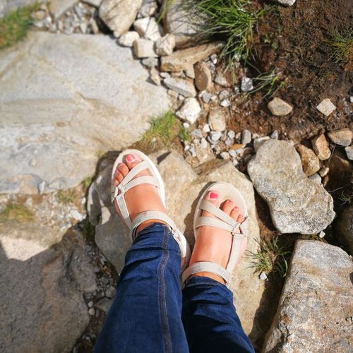Low section of woman wearing sandals standing on rock