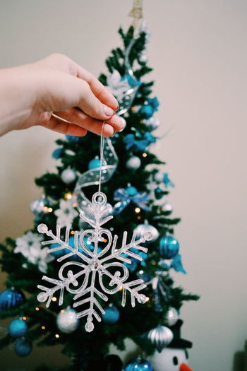 Close-up of cropped holding decoration against christmas tree